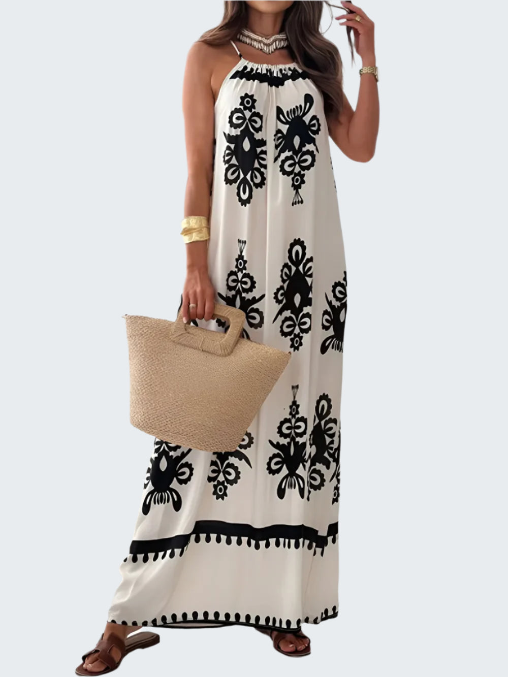 A woman wearing a white and black printed spaghetti strap sleeveless maxi dress with a sheer neckline.