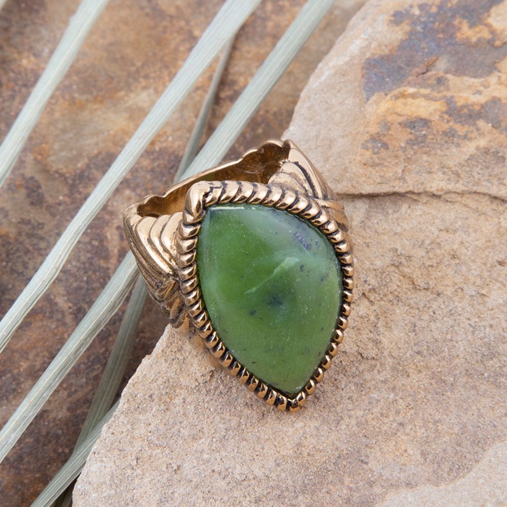 Gold ring with a green stone on a stone surface