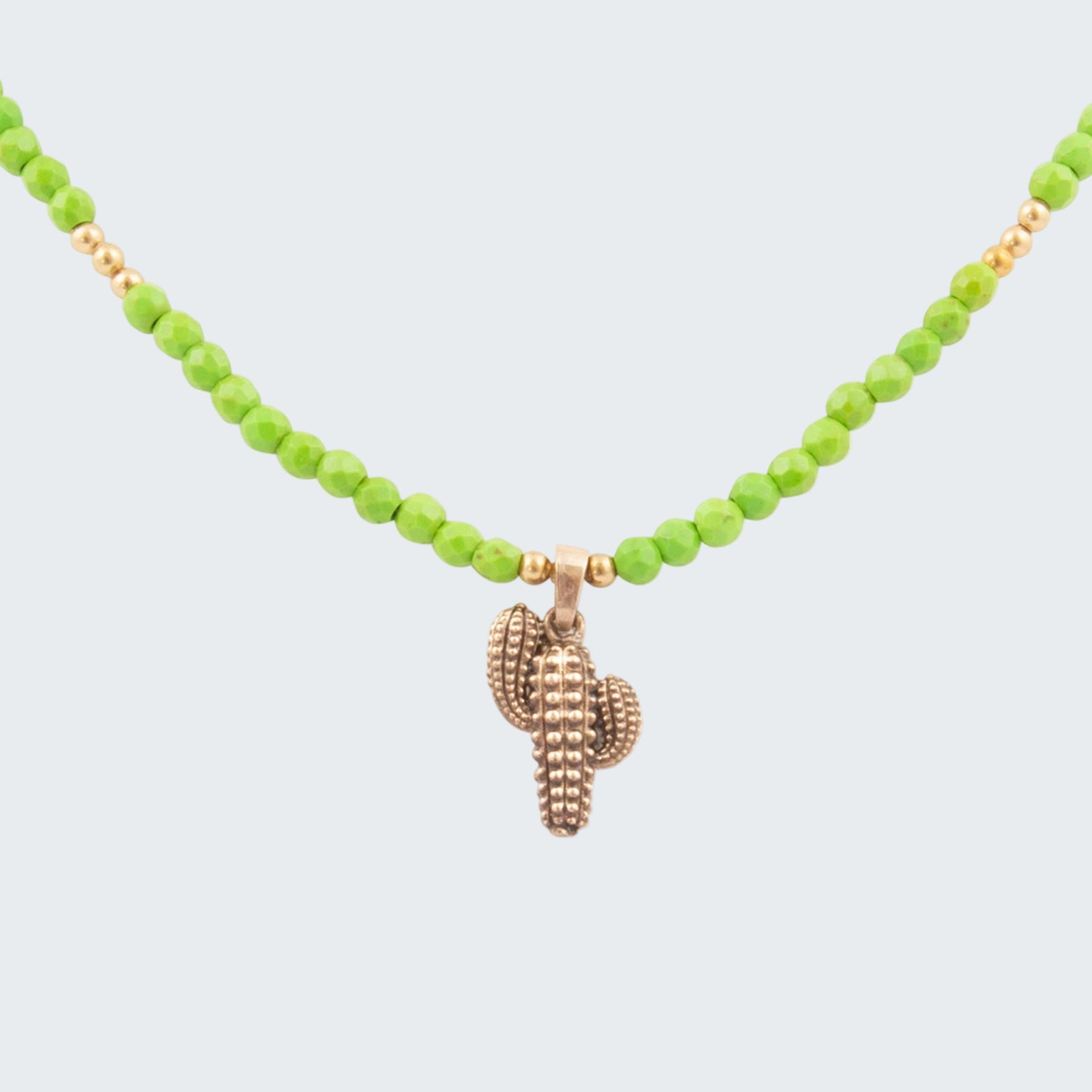 Necklace with green beads and a gold shell pendant on a white background