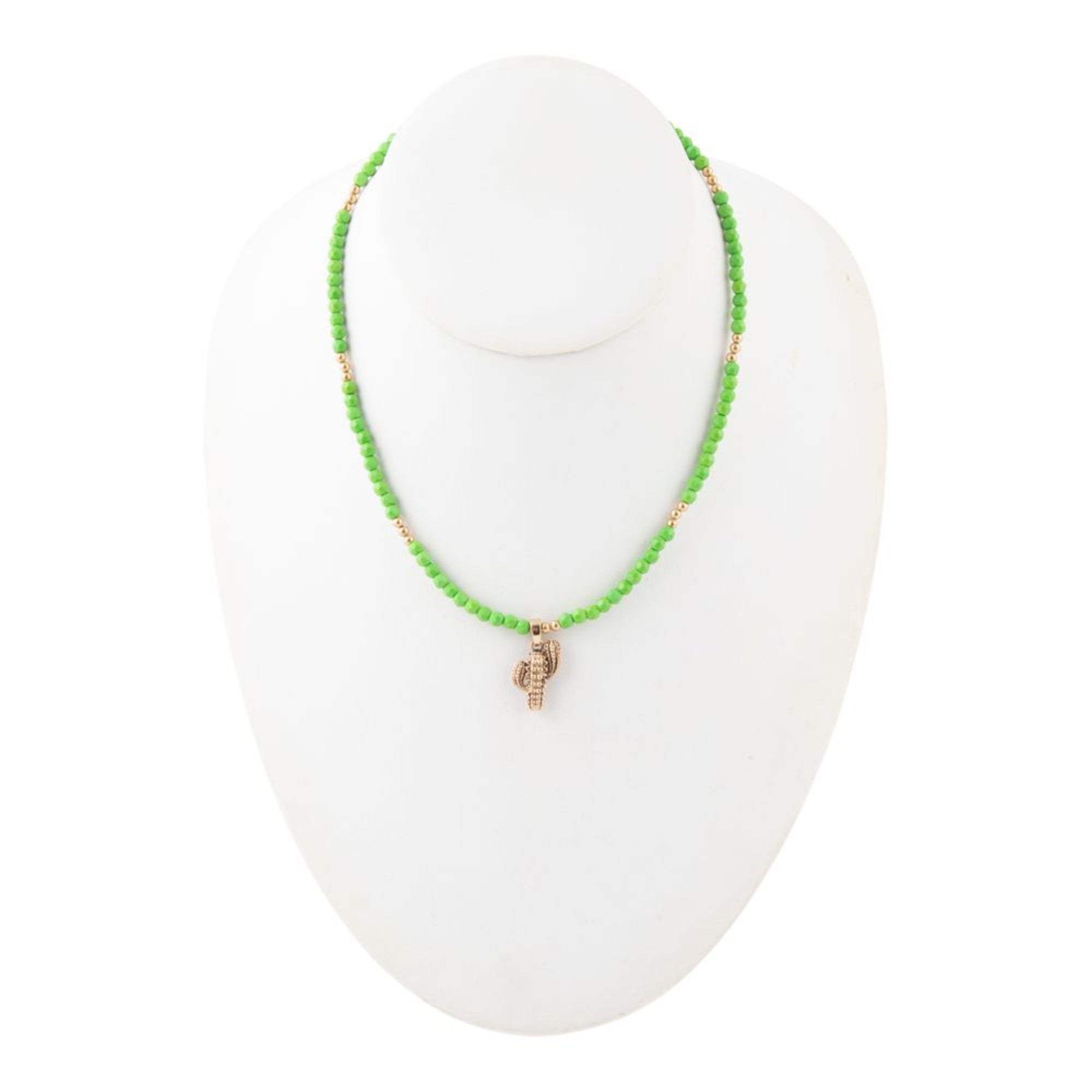 Green beaded necklace with a small gold charm on a white mannequin bust.