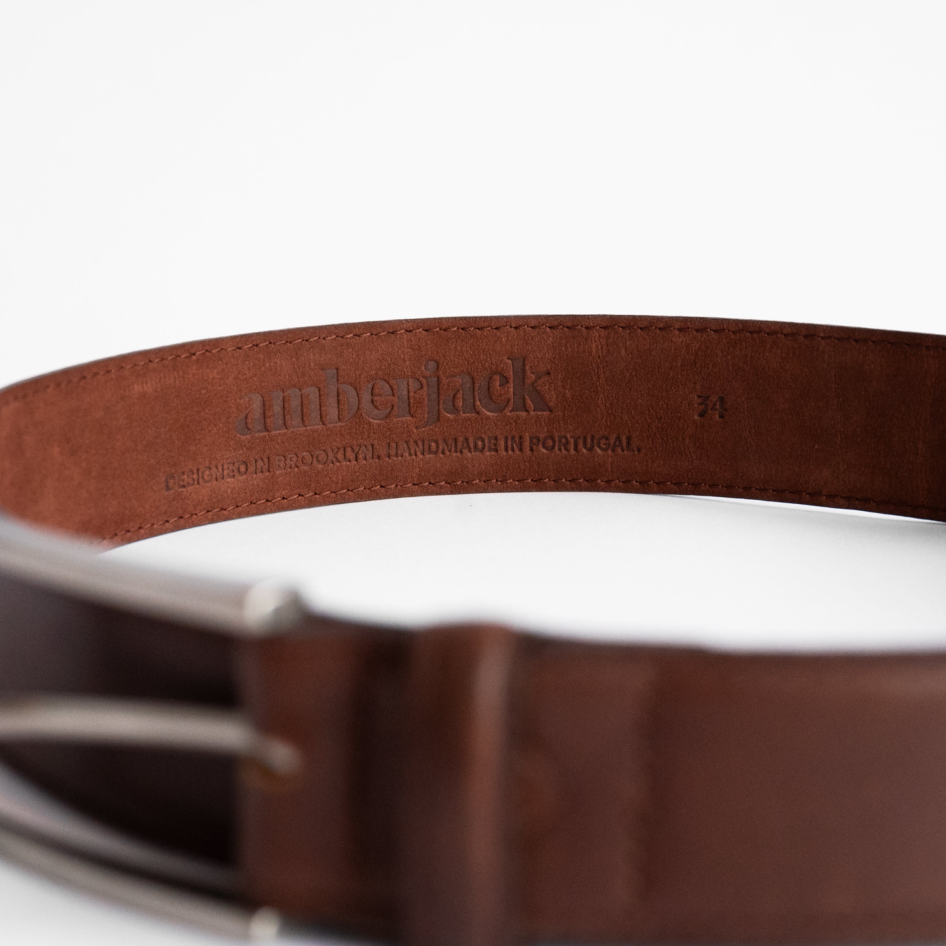 Brown leather belt with 'amberjack' branding on a white background