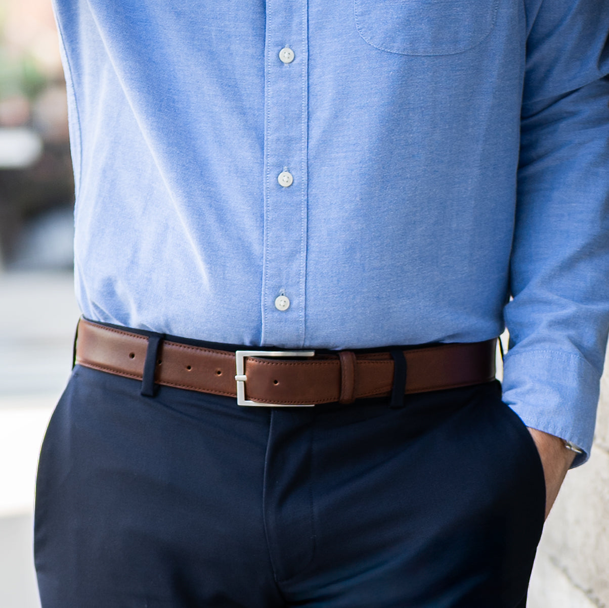 Person wearing a blue shirt and dark pants with a brown belt.