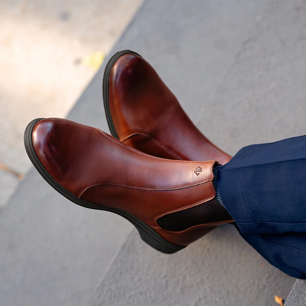 Brown leather shoes worn by a person on a concrete surface
