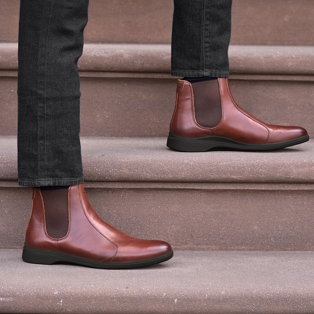 Brown leather Chelsea boots worn on a person standing on steps.