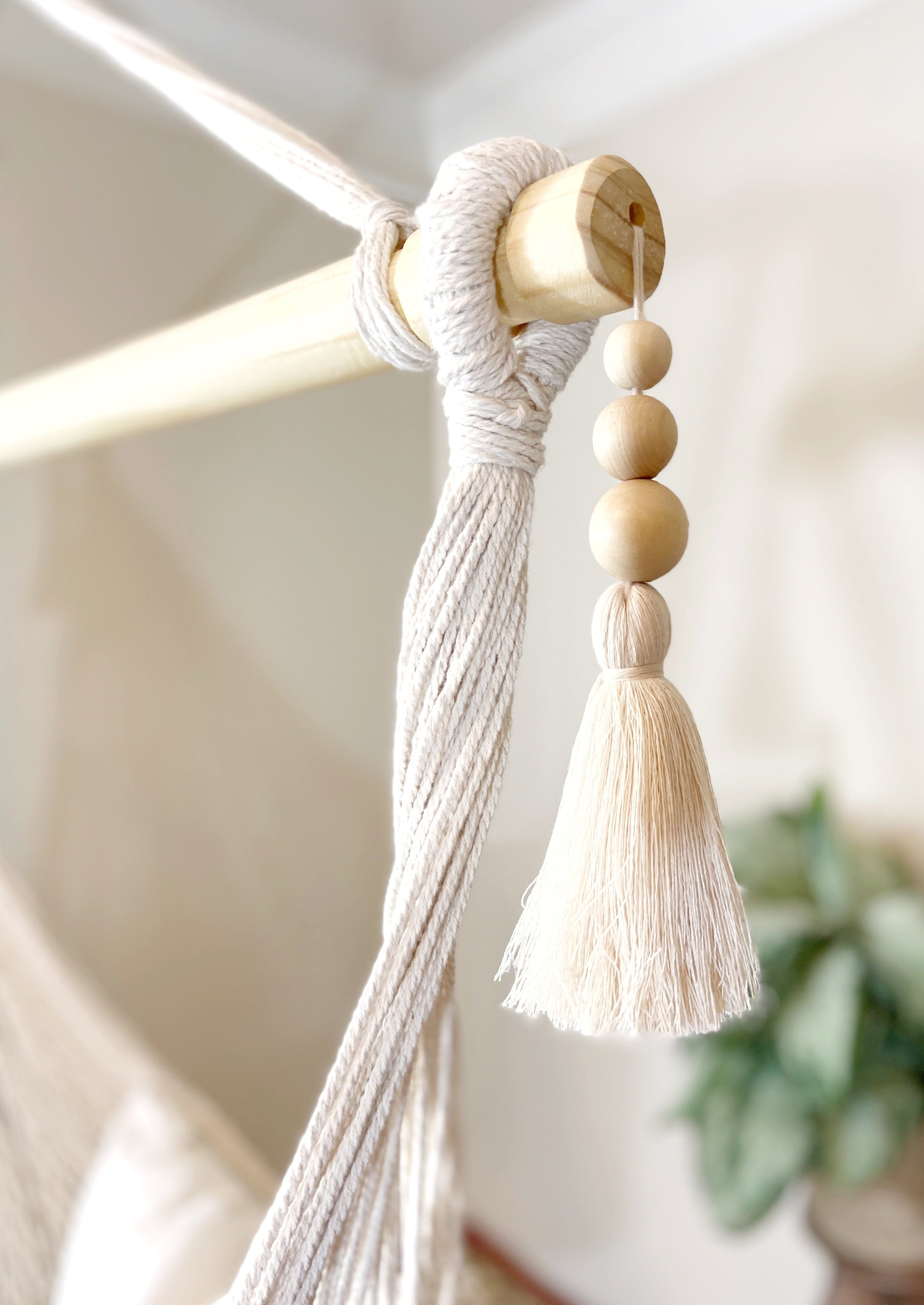 Decorative tassel with wooden beads hanging from a rod.