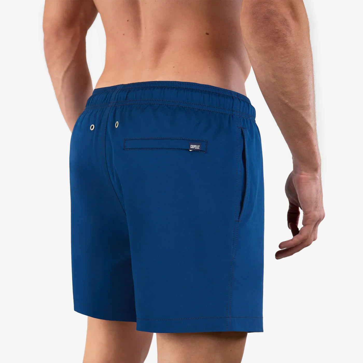 Blue swim shorts worn by a person on a white background