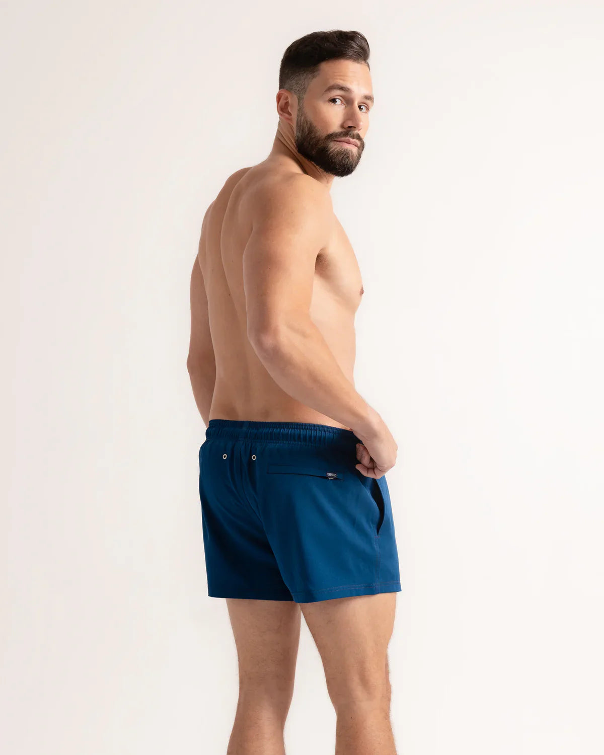 Man wearing blue swim shorts on a white background