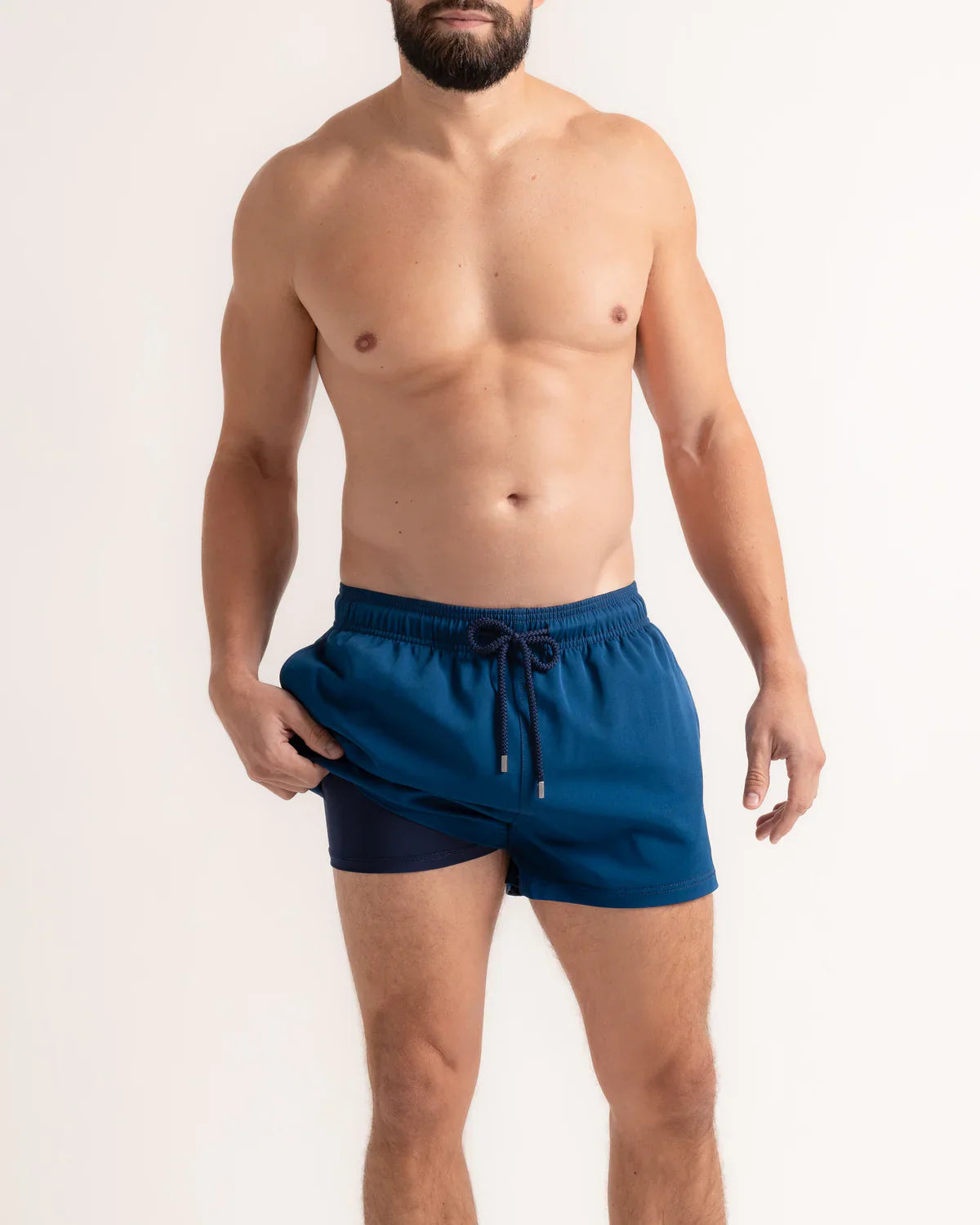 Man wearing blue swim shorts on a plain background