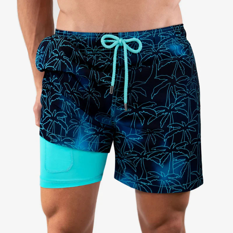 Blue swim shorts with palm tree pattern and turquoise accents on a white background