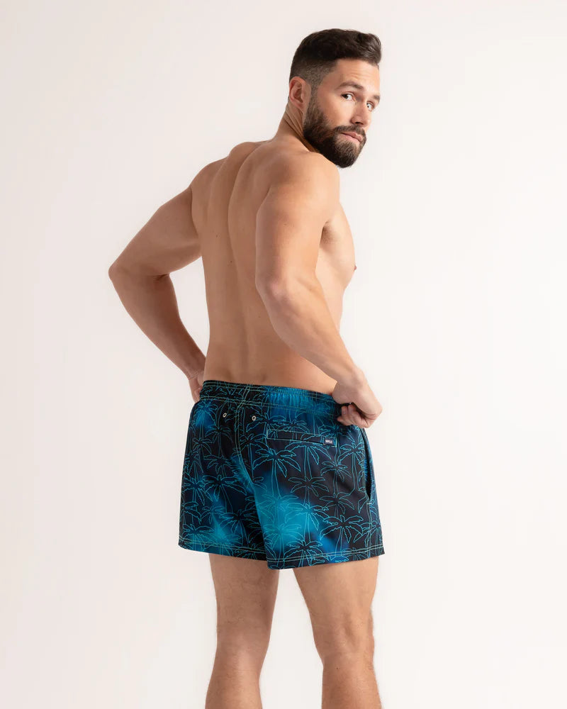 Man wearing blue patterned swim shorts on a white background