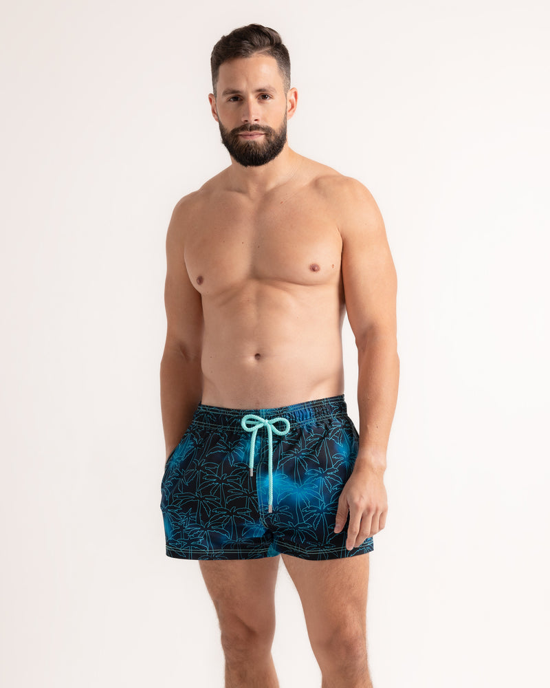 Man wearing blue patterned swim shorts on a white background