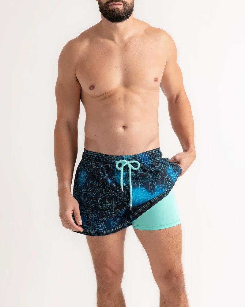 Man wearing blue swim shorts with a white background