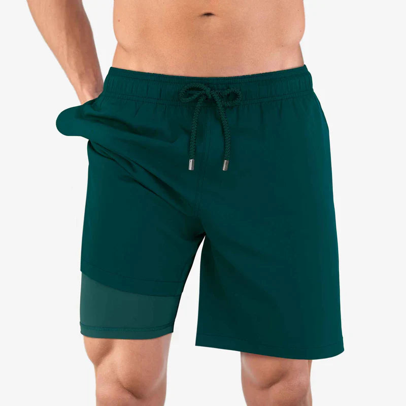 Green swim shorts worn by a person on a white background