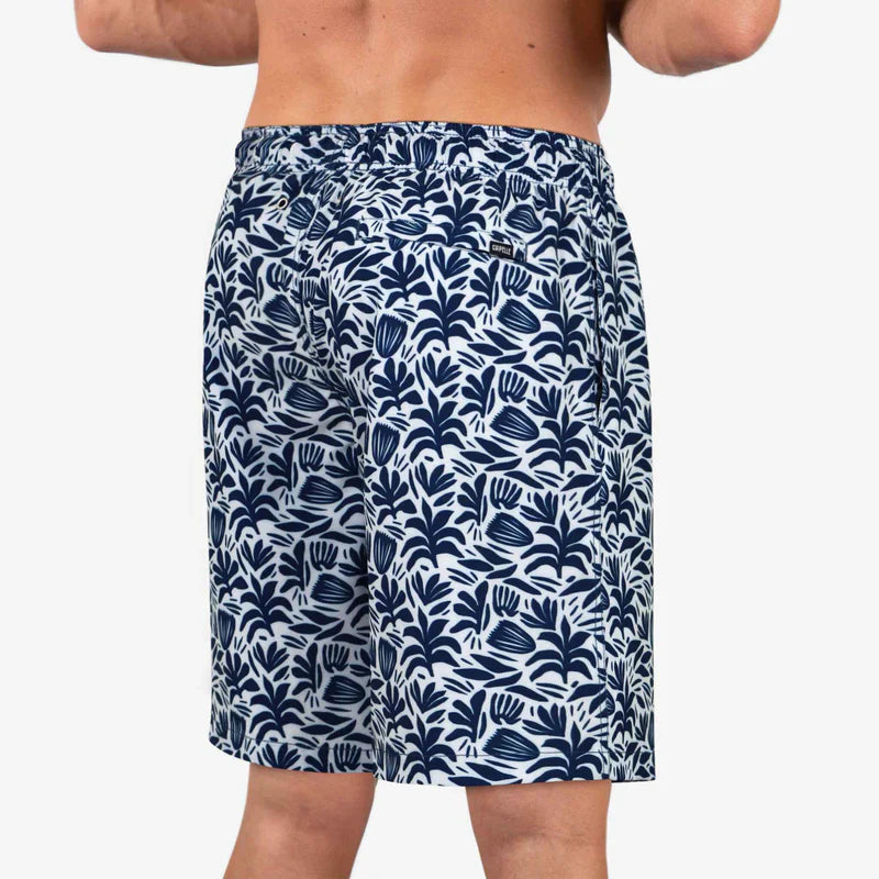 Navy blue swim shorts with white leaf pattern worn by a person on a white background