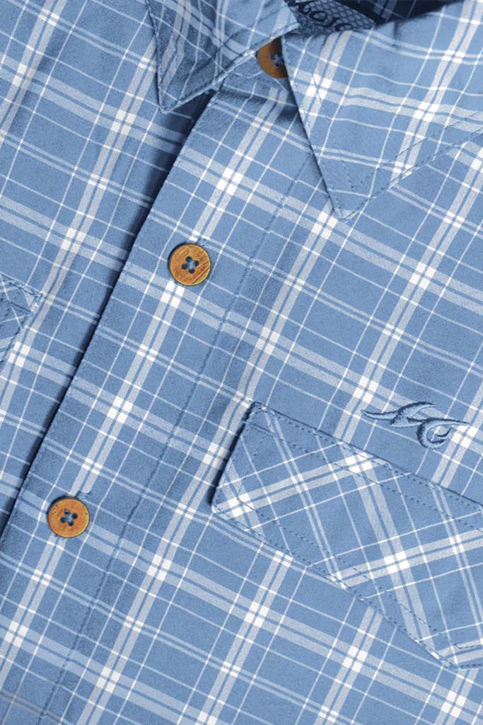 Close-up of a blue plaid shirt with buttons and a logo.