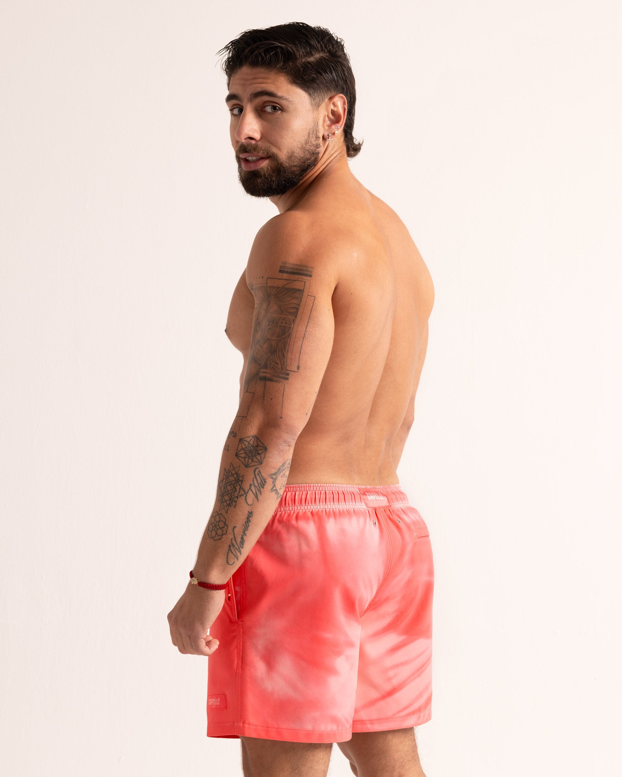 Man wearing pink swim shorts on a plain background