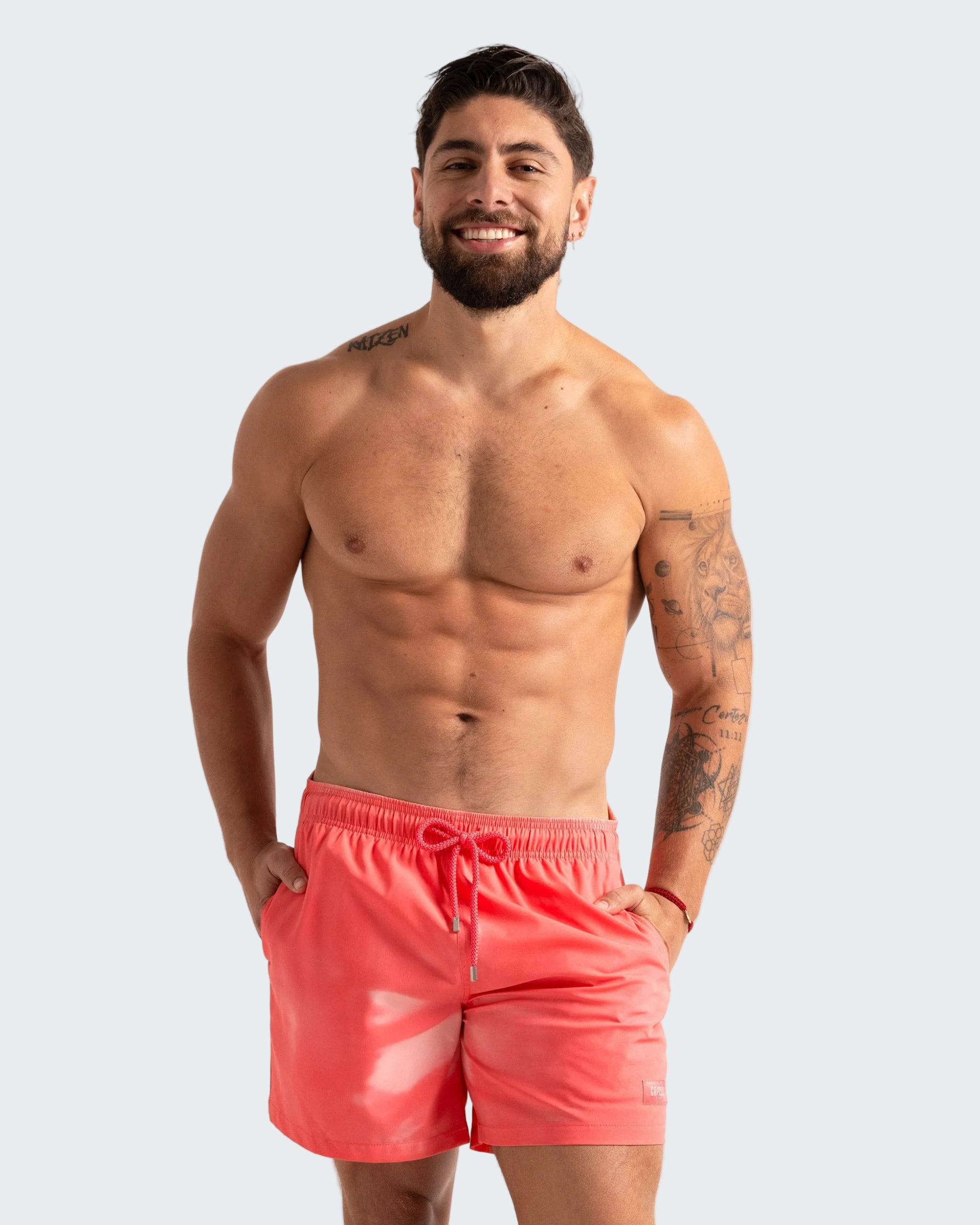 Man wearing pink swim shorts against a plain background