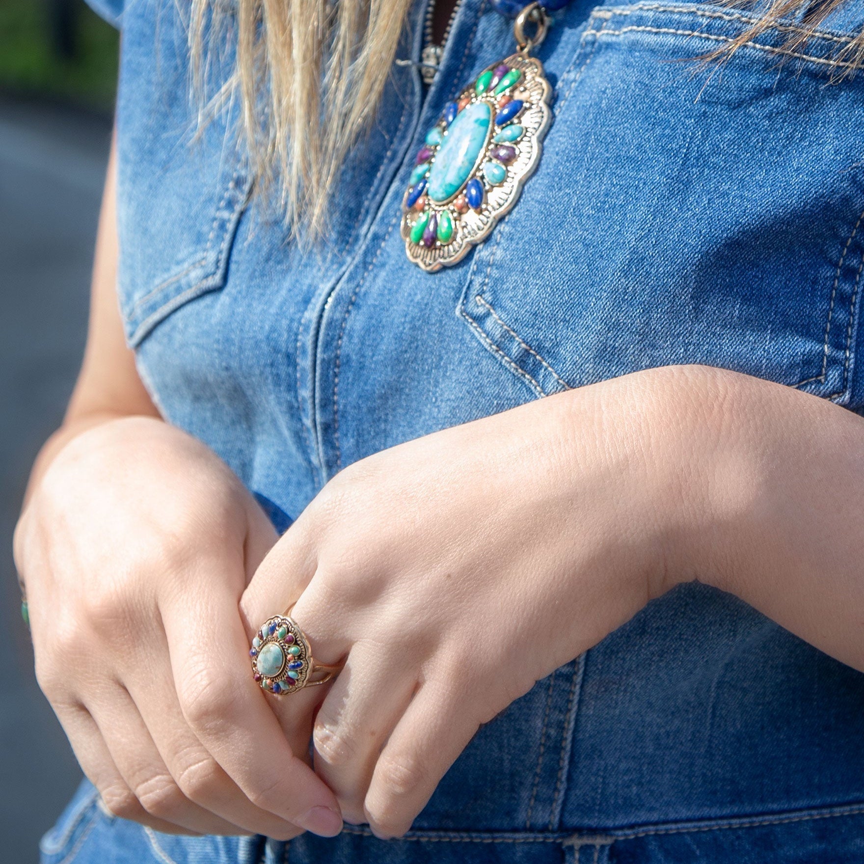 Close-up of a person wearing a colorful ring and denim vest.