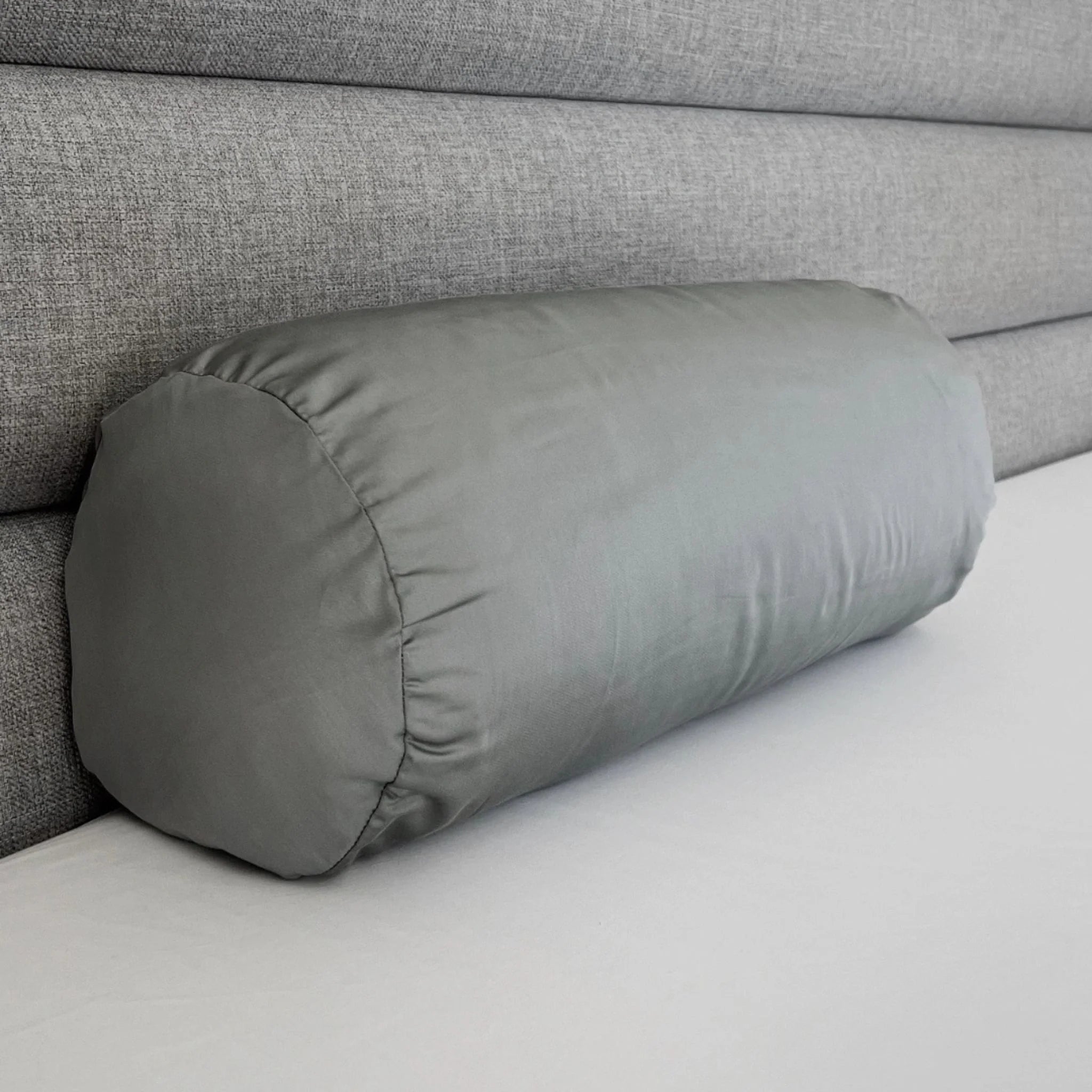 Gray cylindrical pillow on a gray sofa