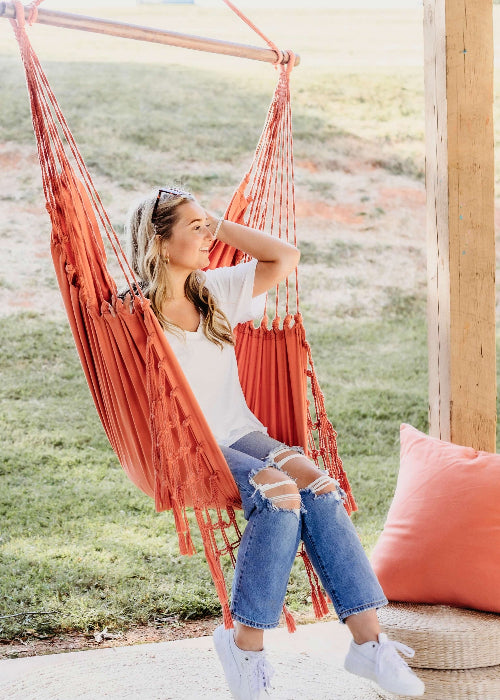 Woman relaxing in a red hammock outdoors with a blurred natural background