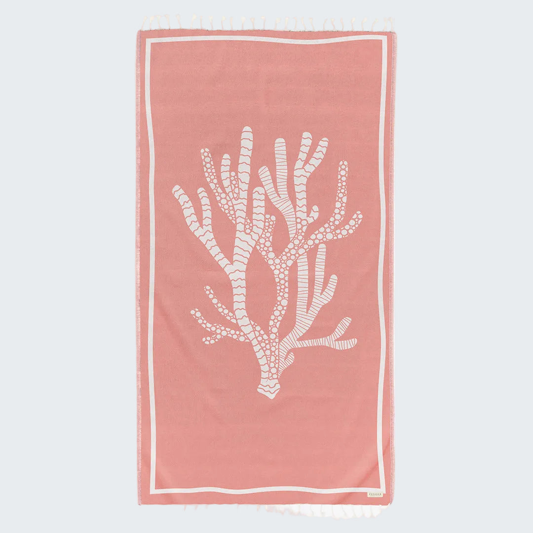 Pink towel with white coral design on a white background
