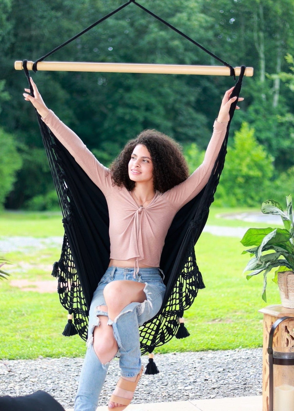 Woman relaxing in a black hammock with greenery in the background