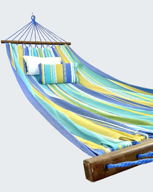 Colorful striped hammock with pillows on a wooden stand in a room.