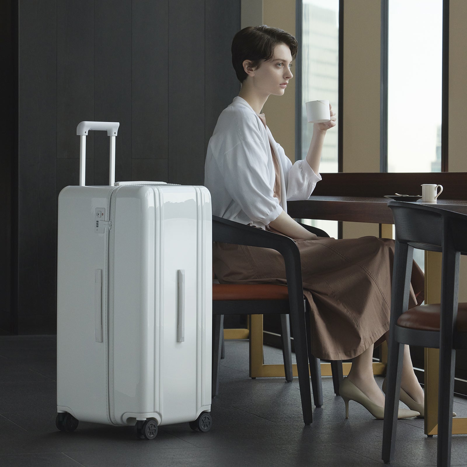 Woman sitting at a table with a white suitcase next to her