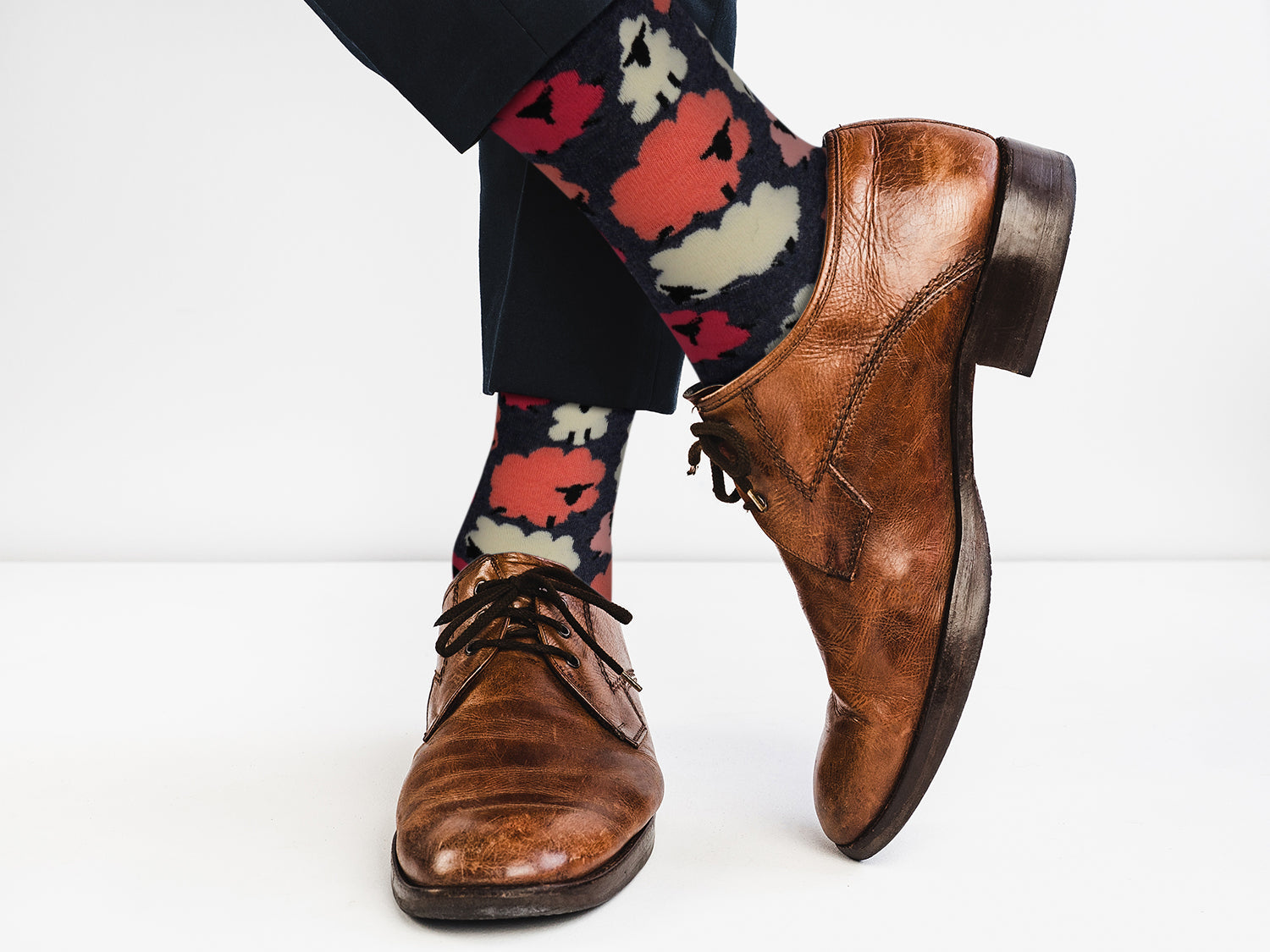 Brown dress shoes and colorful floral-patterned socks on a white background