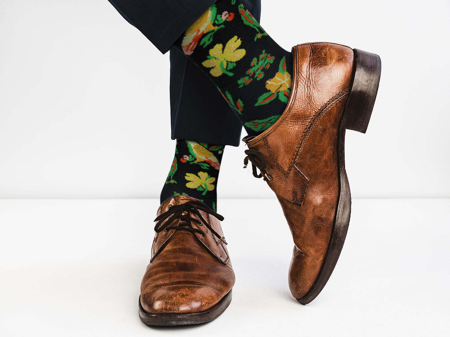 Brown dress shoes and colorful floral-patterned socks on a white background