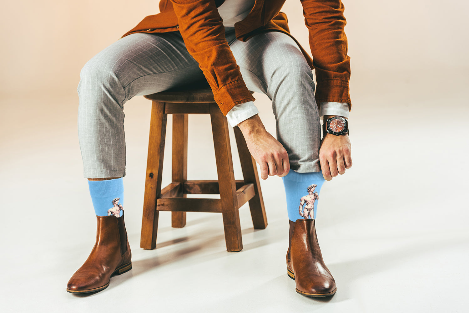 Person wearing blue socks with cartoon characters, sitting on a wooden stool.