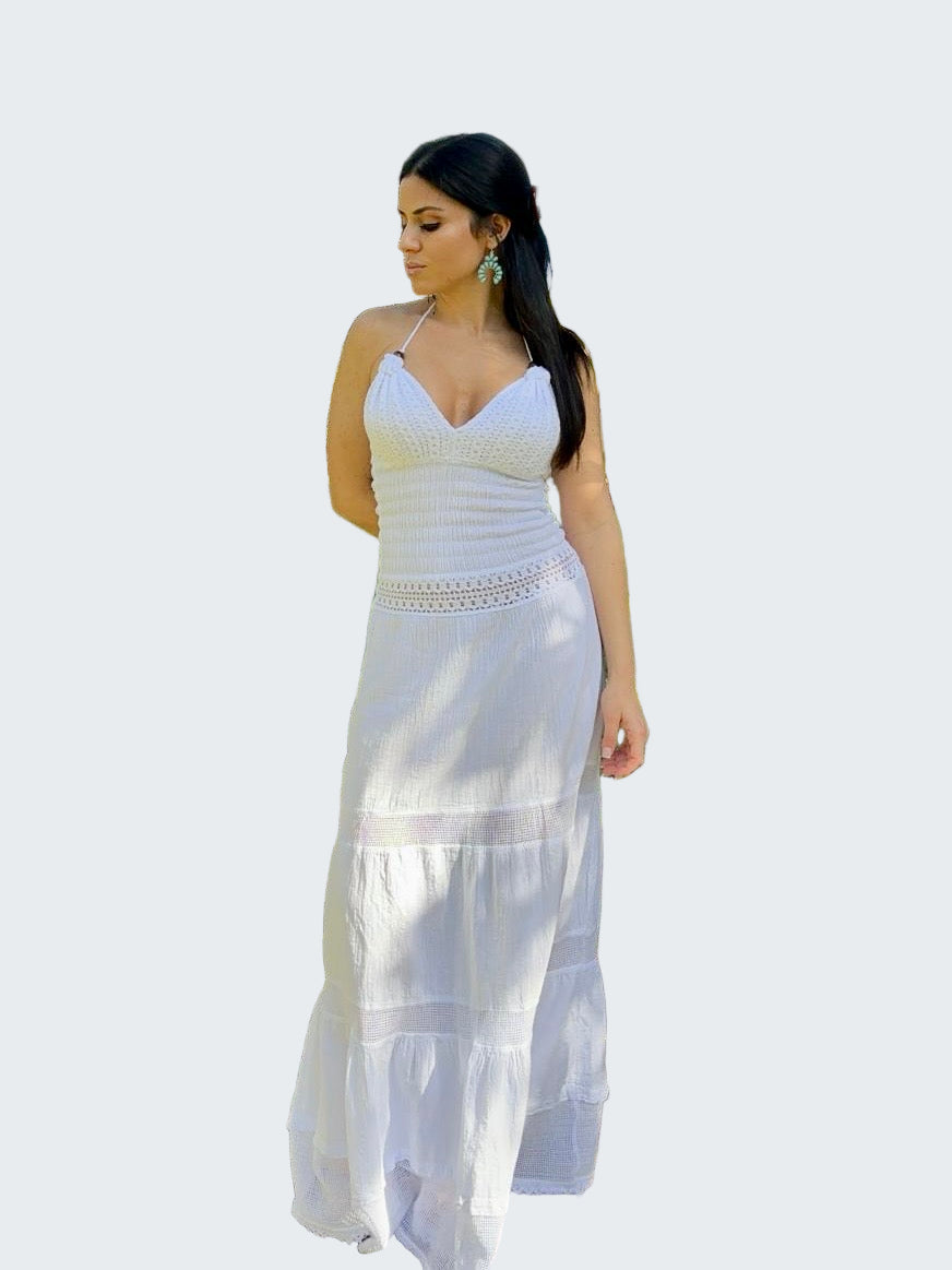 Woman in a white dress standing outdoors near trees and grass