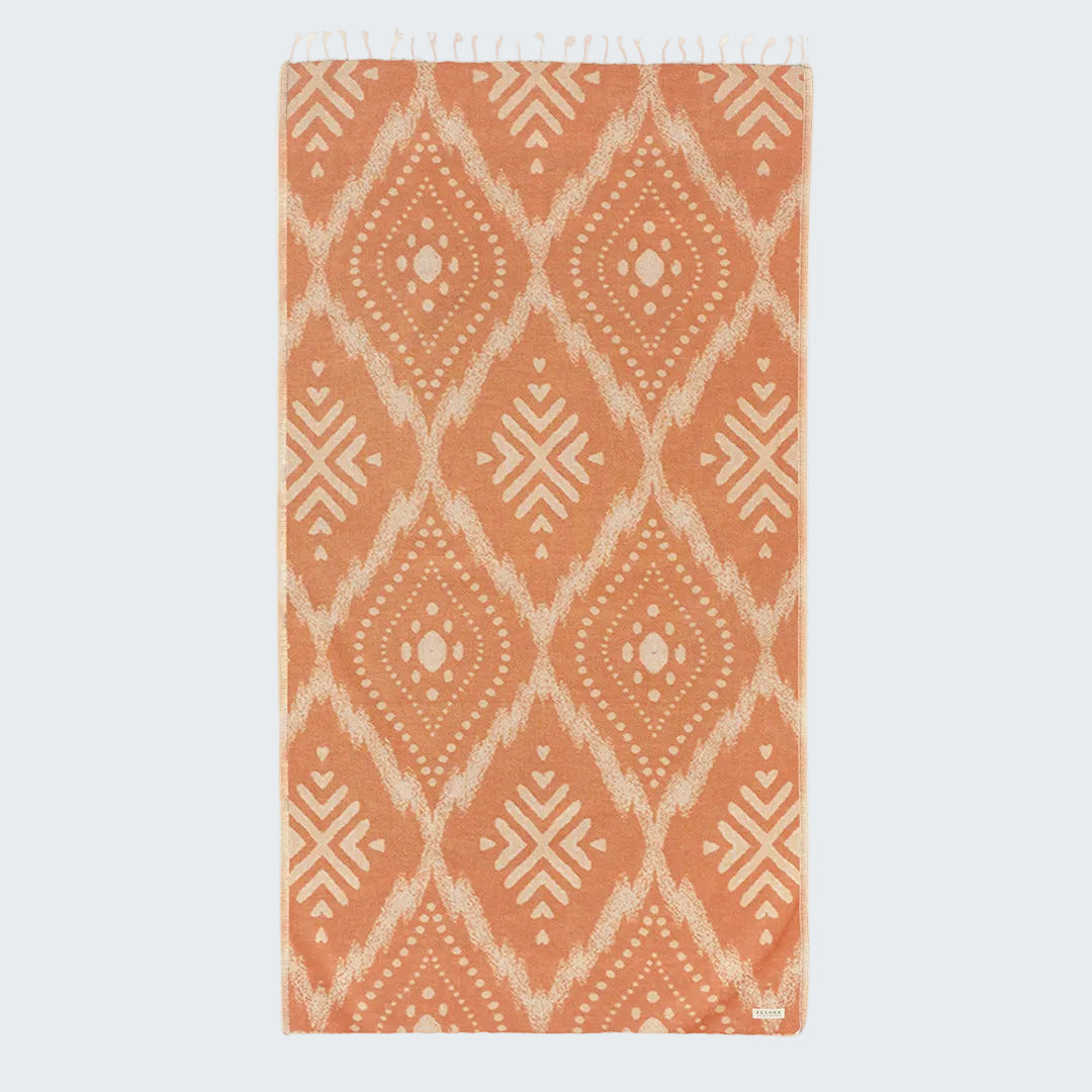 Coral-colored rug with geometric pattern on a white background