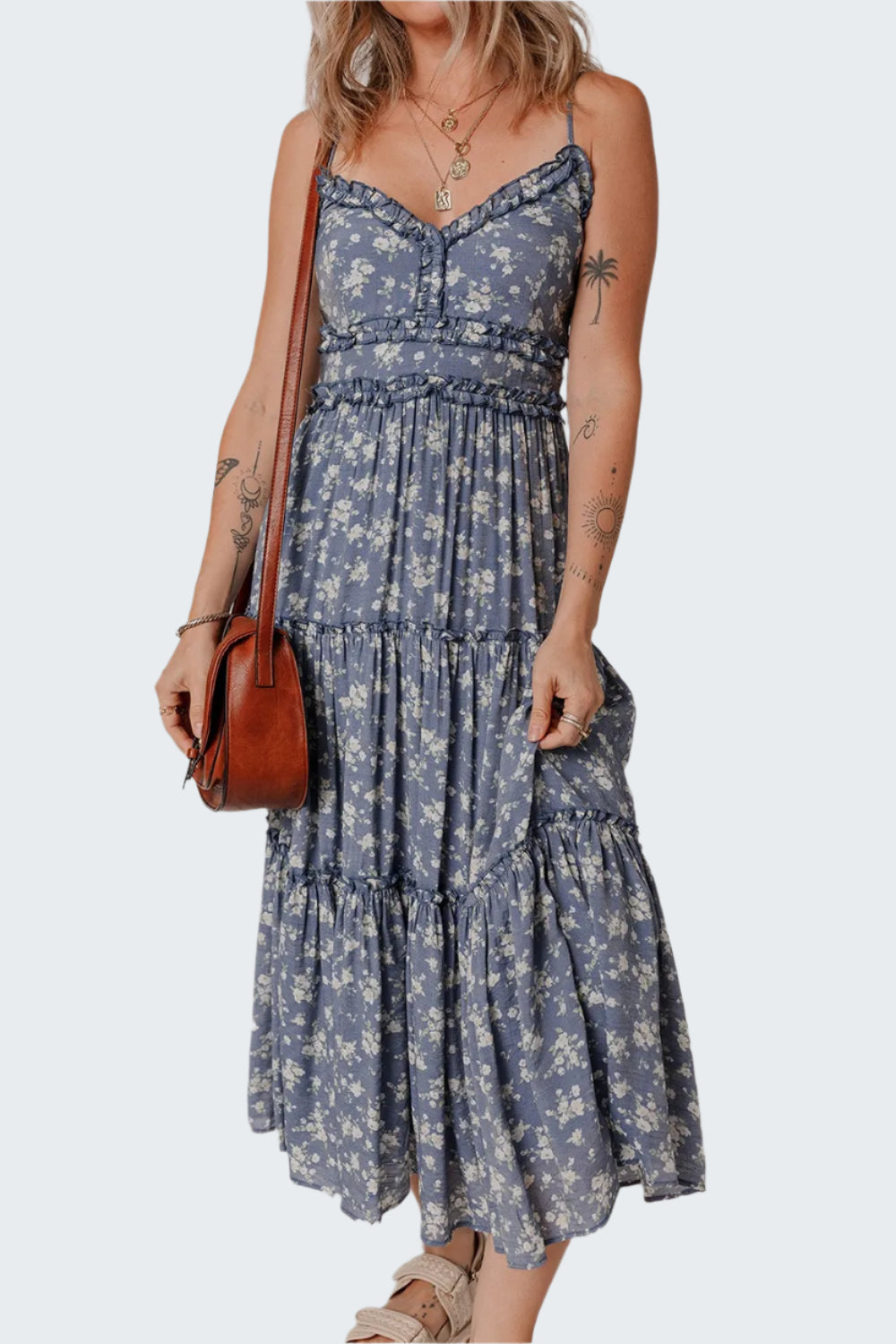 A floral spaghetti strap frilled v neck tiered midi dress in blue and white, with a brown belt and brown accessories.