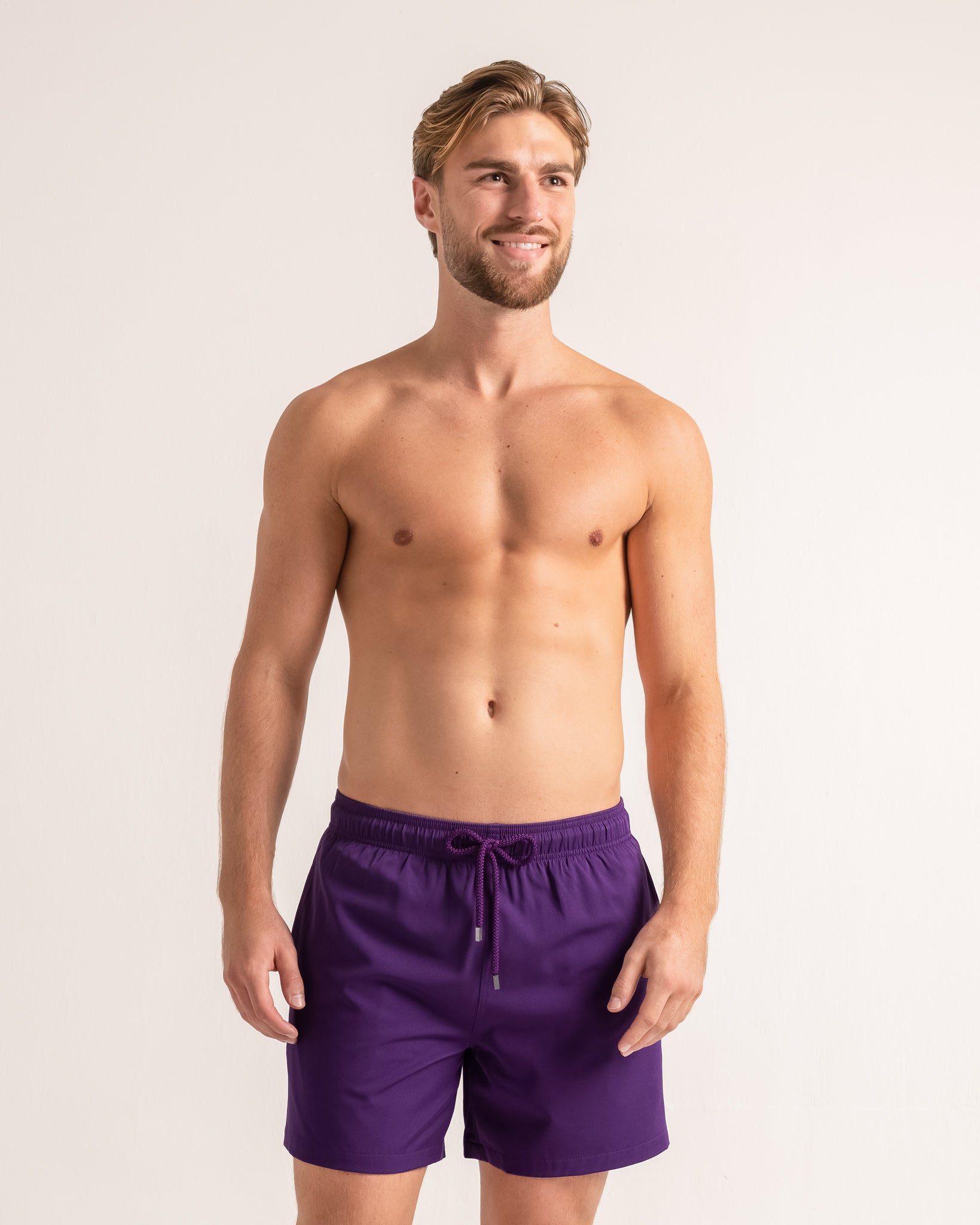 Man wearing purple swim shorts against a plain background