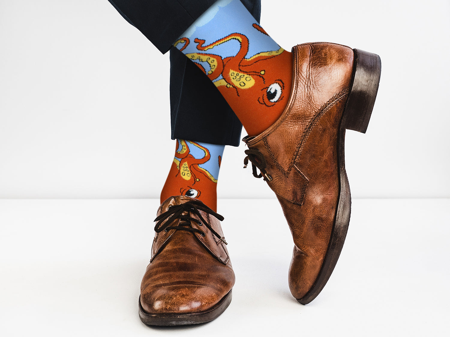 Brown dress shoes with cartoon octopus socks on a white background