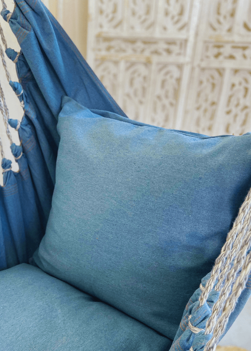 Blue cushion on a hammock chair with a textured wall in the background
