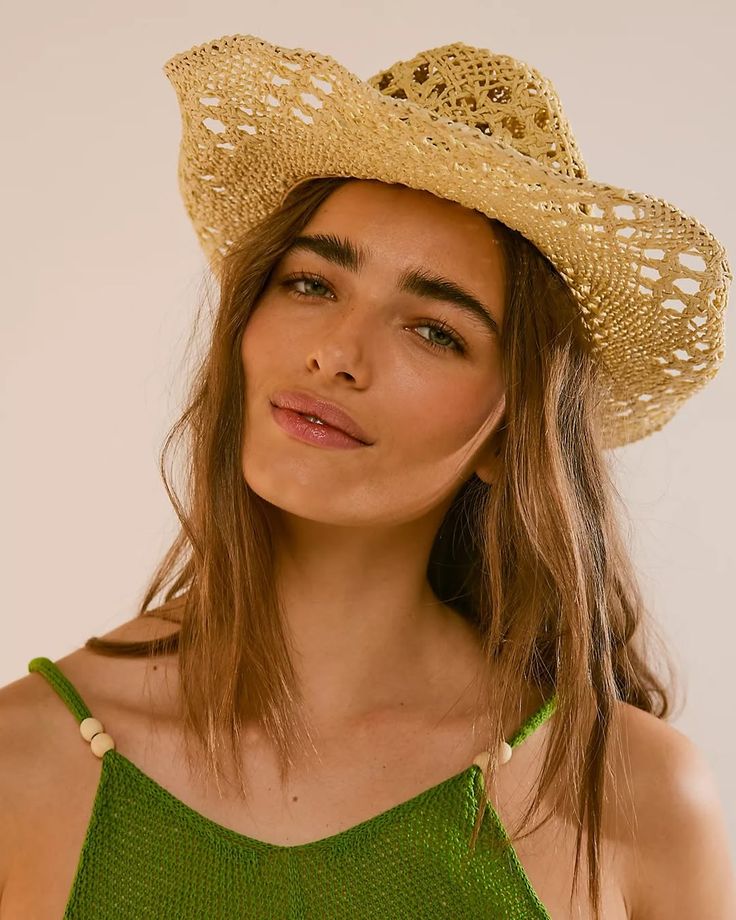 Woman wearing a straw hat and green top against a beige background