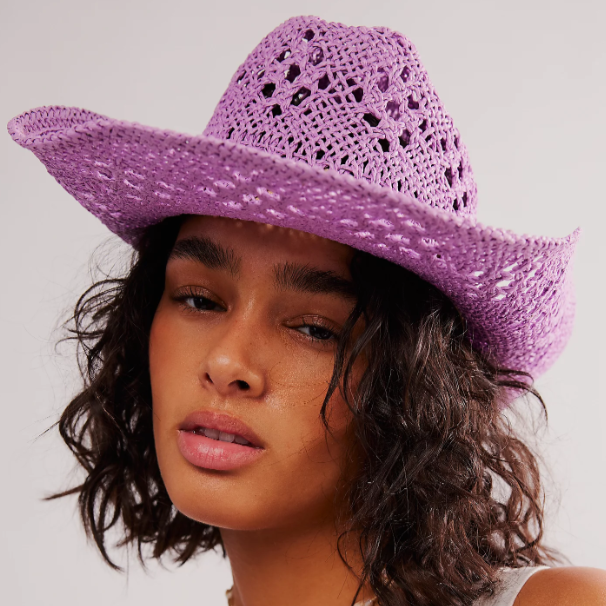 Woman wearing a purple crochet hat against a plain background