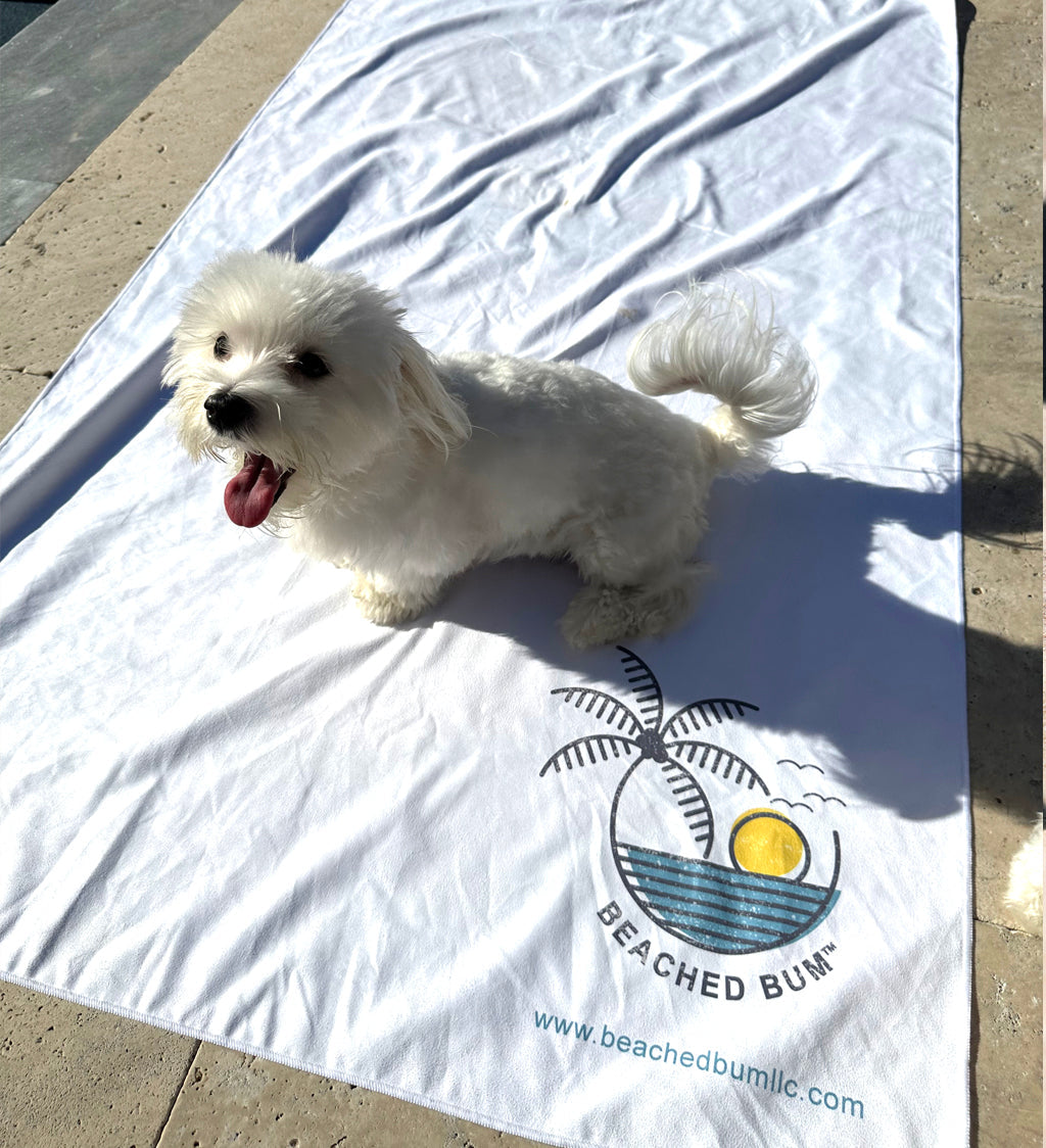 White dog on a white towel with 'Beached Bum' logo