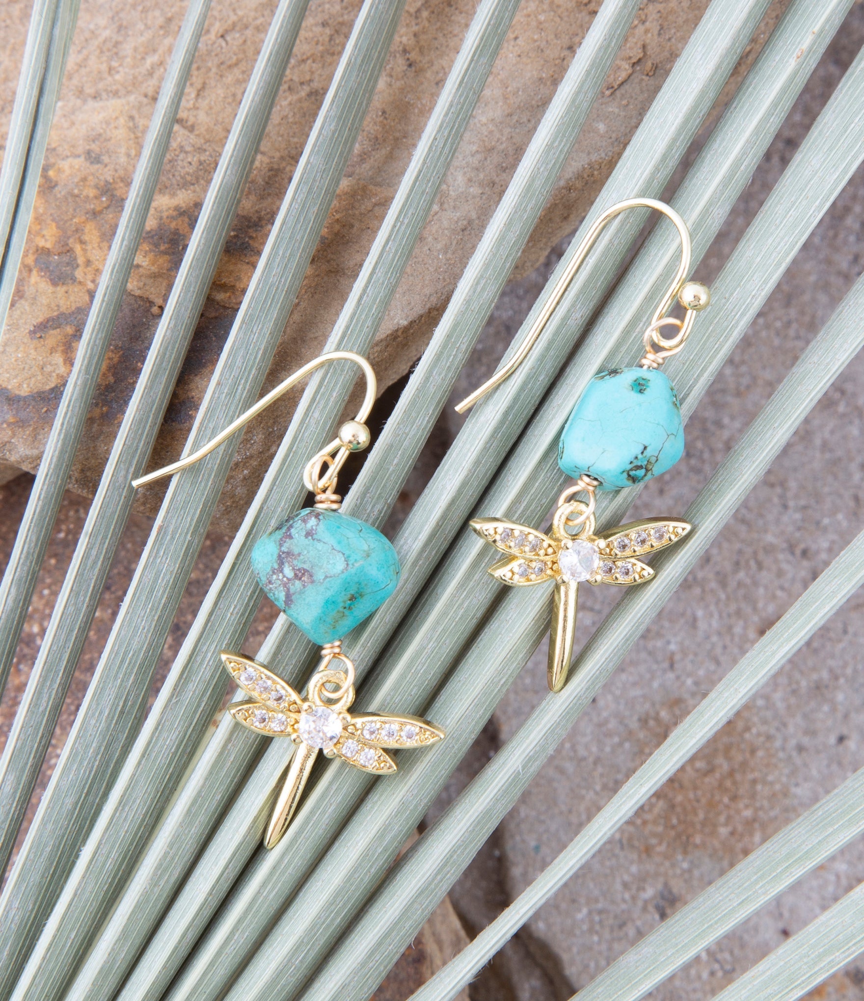 Dragonfly-shaped earrings with turquoise beads on a natural background