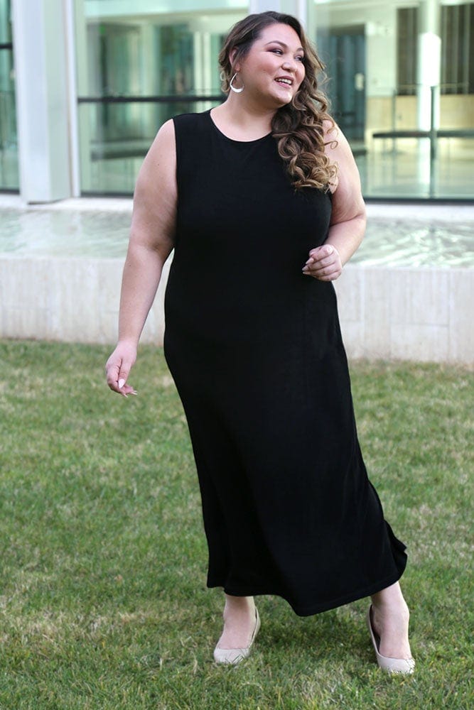 Woman wearing a black sleeveless dress standing outdoors.