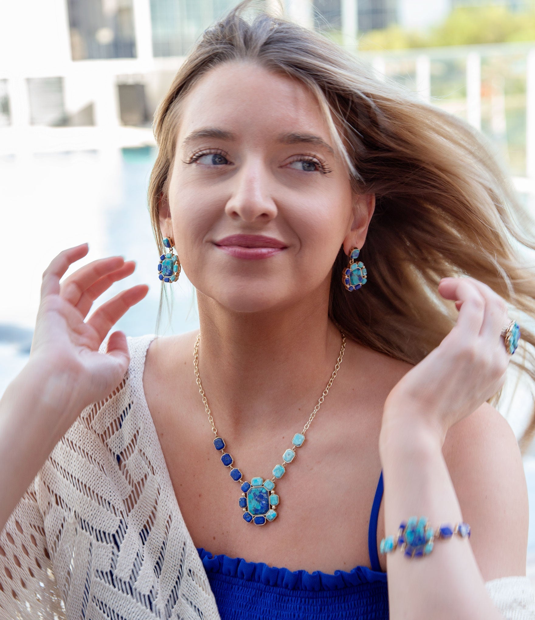 Woman wearing blue jewelry with a blurred outdoor background