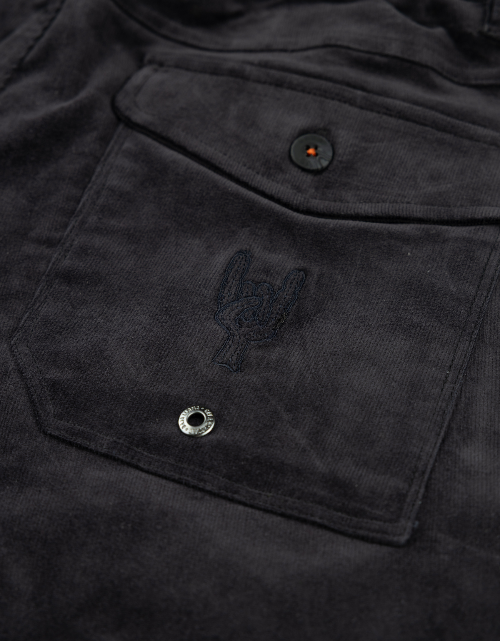 Close-up of a black jacket pocket with an embroidered logo on a dark background