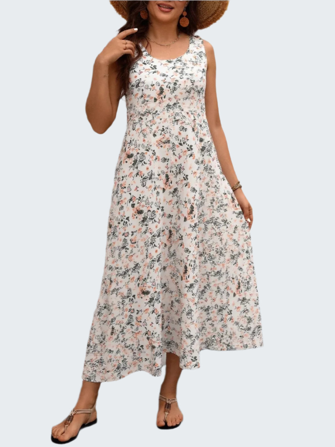 A model wearing a plus size floral tank dress with pockets, standing in front of a white wooden background.