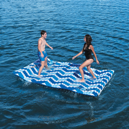 Two people on a blue and white patterned inflatable raft in the water.
