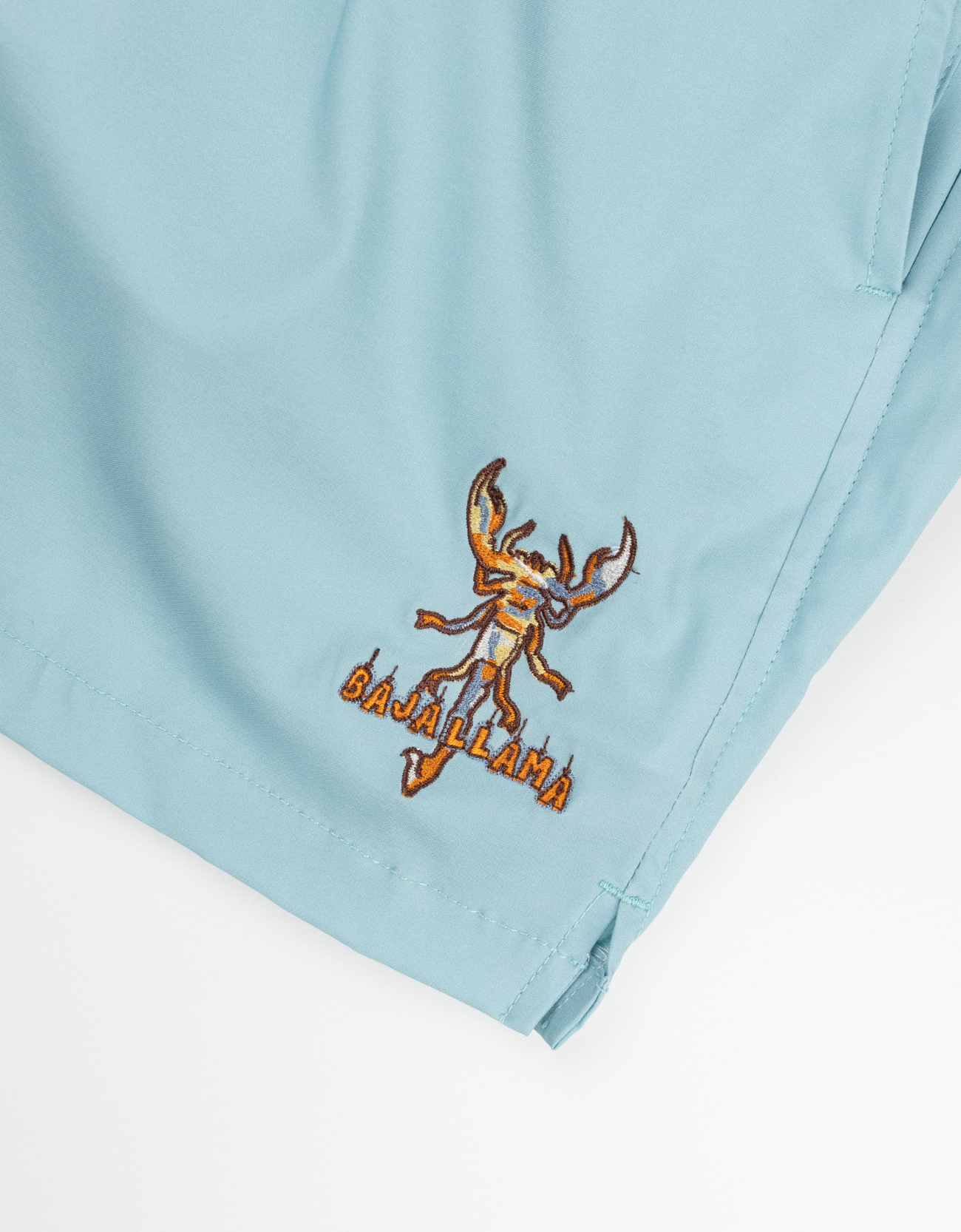 Light blue fabric with an embroidered design of a lobster and 'Baja Llama' text on a white background.