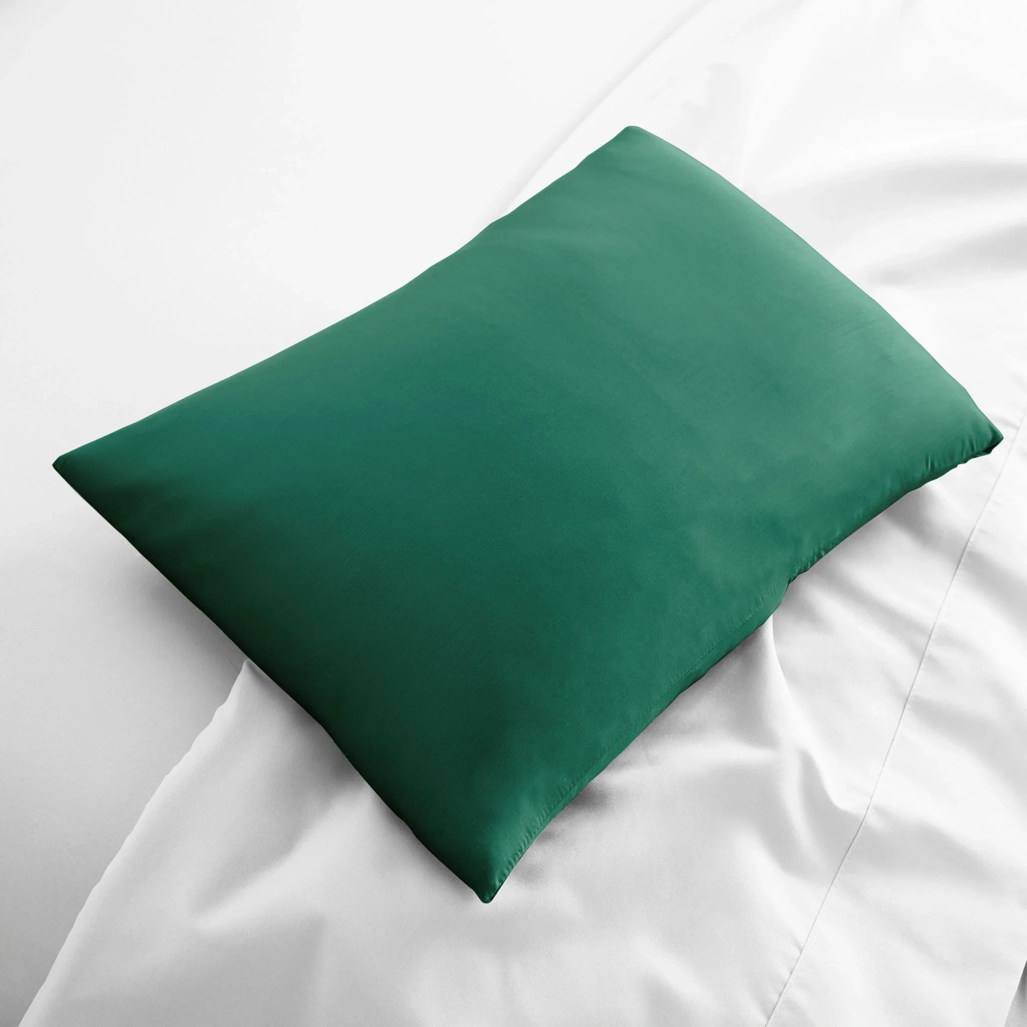 Green pillow on a white bed
