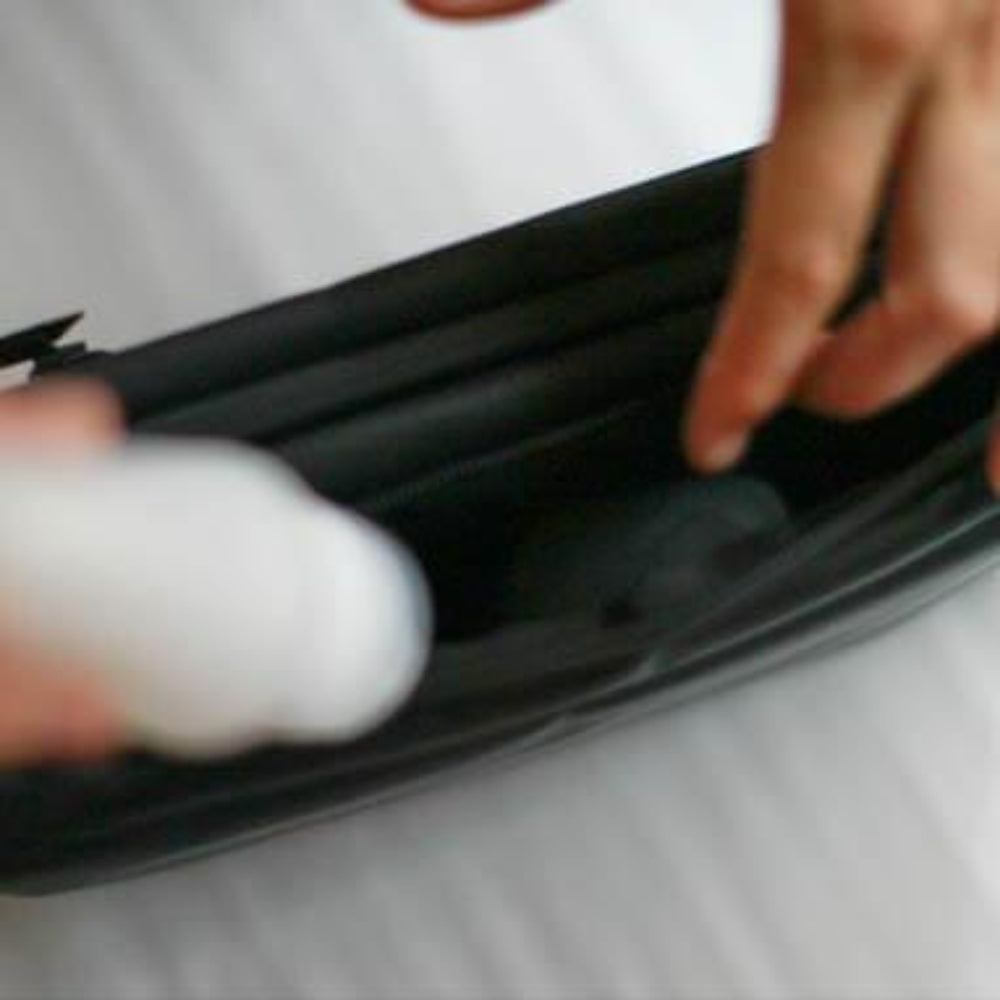 Person using a white object to clean inside a black container.