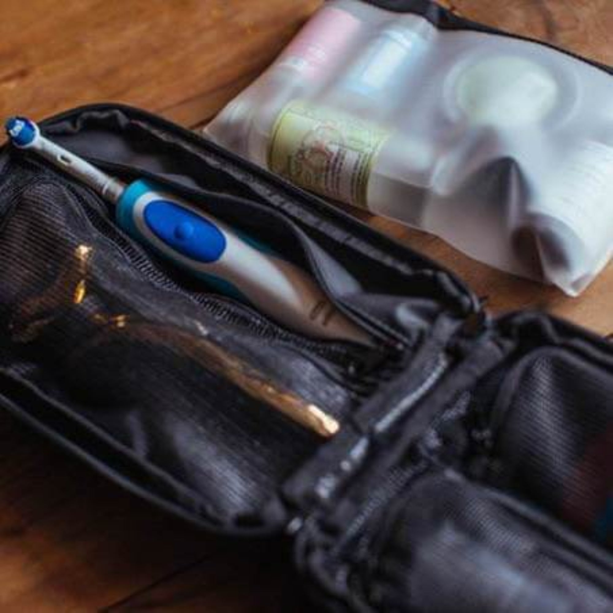 Electric toothbrush in a black case with a bottle of mouthwash on a wooden surface